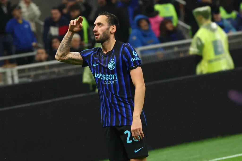 Hakan Calhanoglu con la maglia dell'Inter numero 20 durante una partita, rivolto verso la tribuna sotto la pioggia