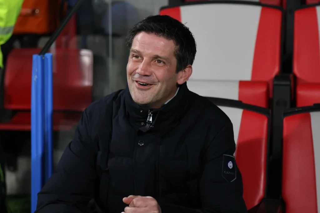 Cristian Chivu in panchina durante una partita, indossa una giacca nera con il logo Inter