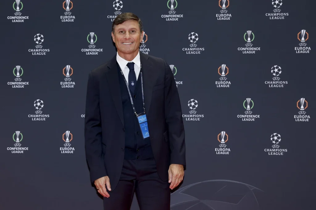 Javier Zanetti in abito scuro con accredito UEFA davanti a uno sfondo con loghi delle competizioni europee