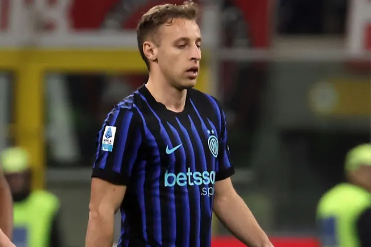 Giocatore dell'Inter in maglia a strisce blu e nera durante una partita, sguardo concentrato in campo