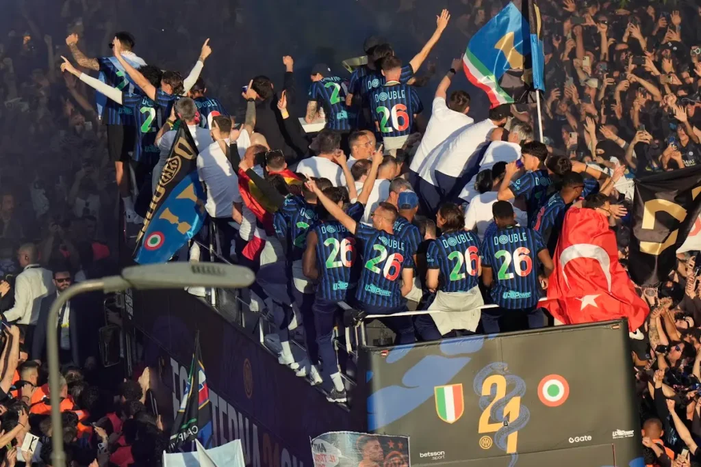 Giocatori dell'Inter sul bus scoperto con maglie numero 26, bandiere tricolori e tifosi sugli spalti durante i festeggiamenti