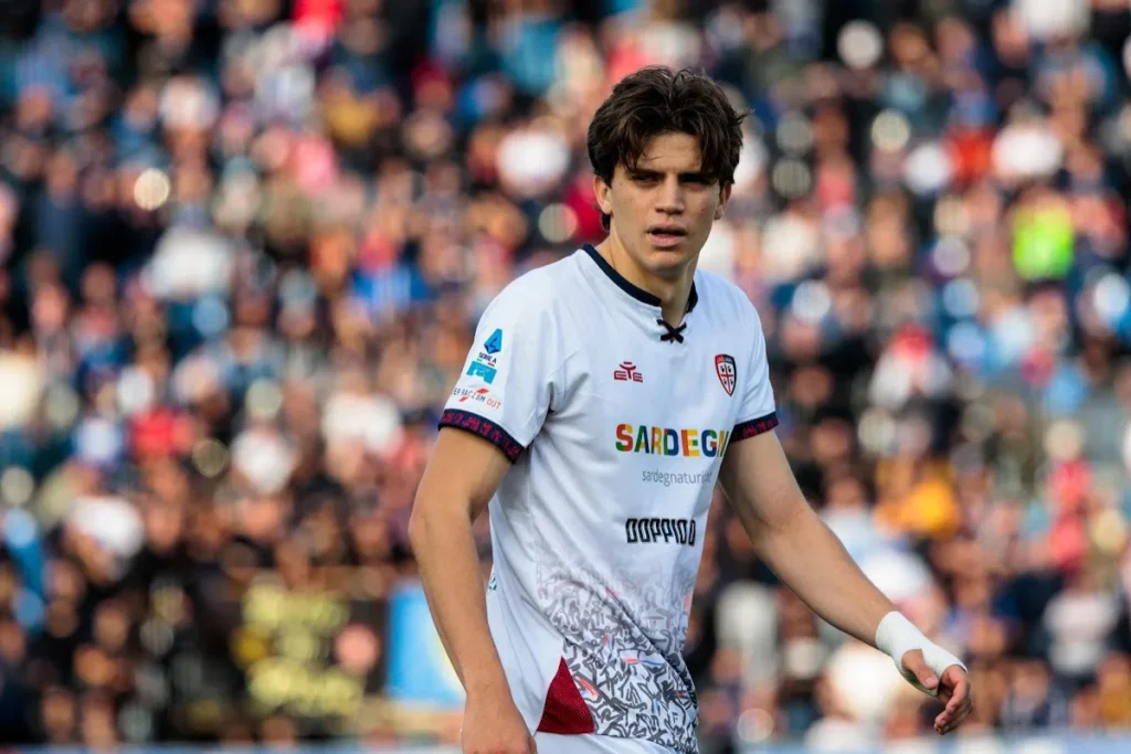 Giocatore del Cagliari in maglia bianca con sponsor Sardegna durante una partita in stadio