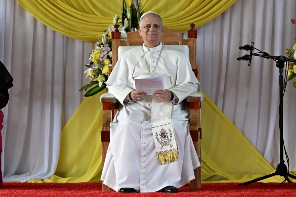 Papa Leone XIV in abiti pontificali seduto su una sedia durante un evento ufficiale