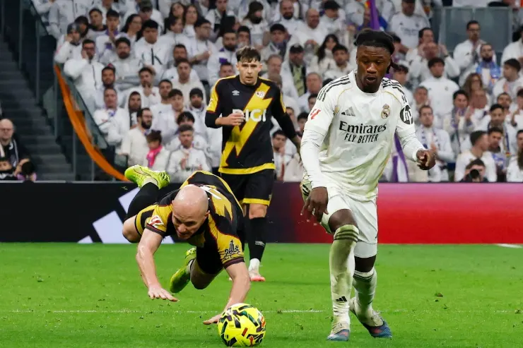 Camavinga in contrasto di gioco durante una partita del Real Madrid, con avversario in maglia bianca e folle sullo sfondo