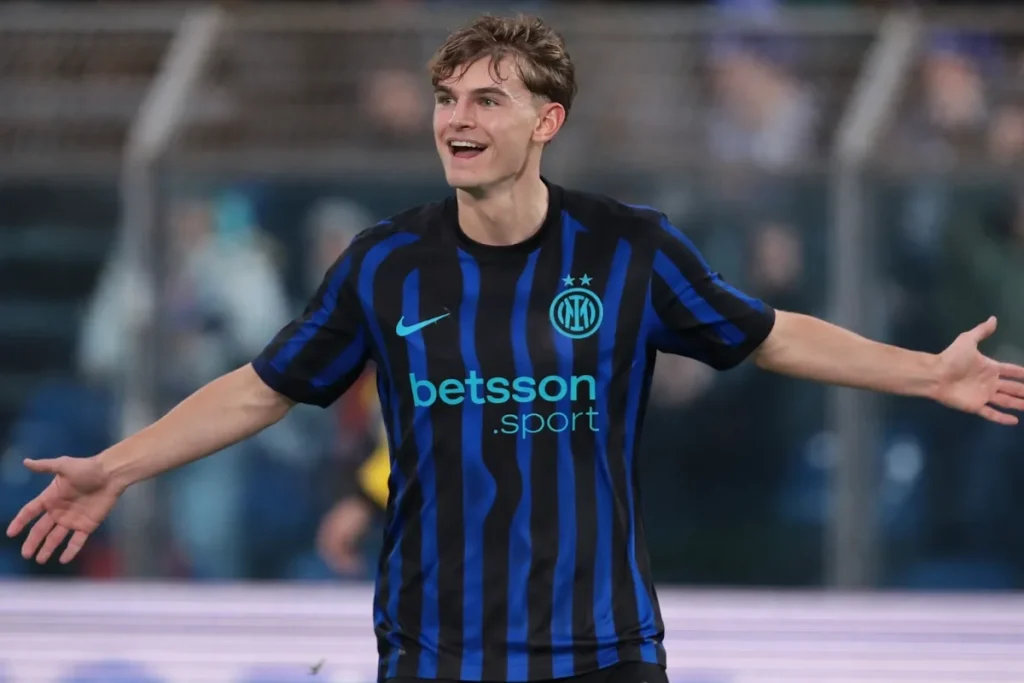 Nico Paz in maglia Inter a righe blu e nere, sorridente con le braccia allargate durante una partita