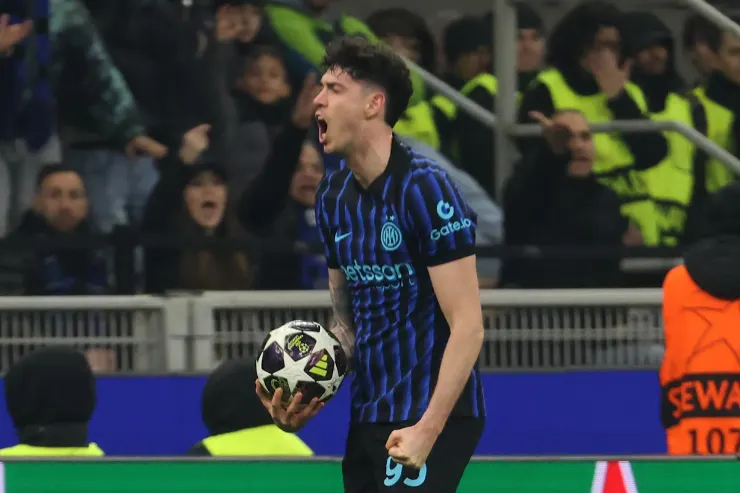 Bastoni esulta durante una partita dell'Inter, indossa la maglia nerazzurra a righe e tiene il pallone in mano