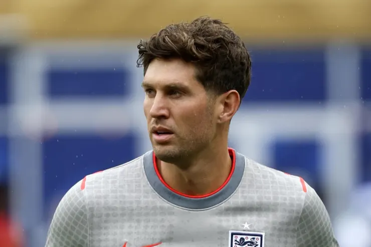 John Stones in maglia da allenamento grigia con colletto rosso, durante una sessione di allenamento