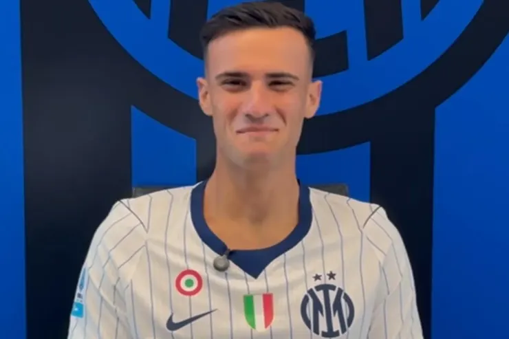 Stankovic in maglia Inter a righe bianche e blu, con lo stemma nerazzurro sullo sfondo