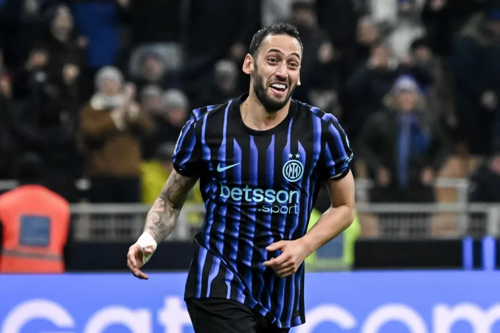 Calhanoglu sorride durante una partita dell'Inter, indossa la maglia nerazzurra a righe