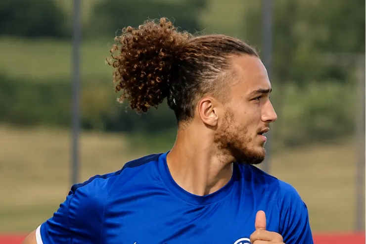 Giocatore dell'Inter in maglia blu durante l'allenamento, di profilo con capelli raccolti