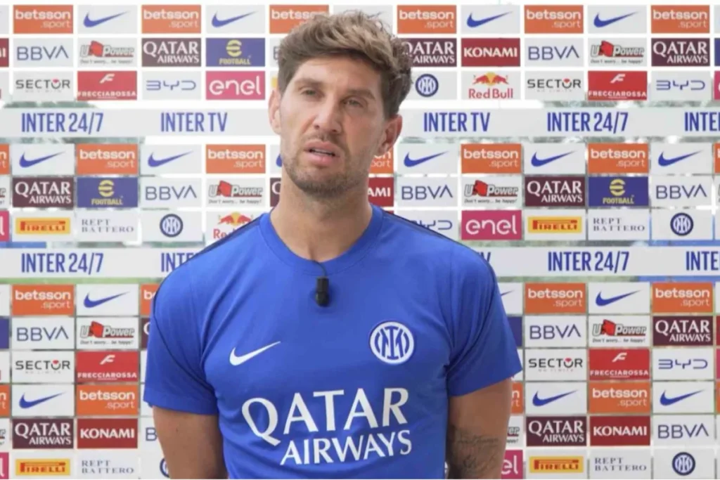 John Stones intervistato davanti alla parete pubblicitaria Inter con maglia blu Qatar Airways