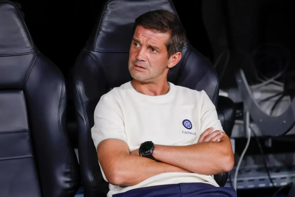 Cristian Chivu seduto in panchina con braccia incrociate, indossa maglietta bianca con logo Canale
