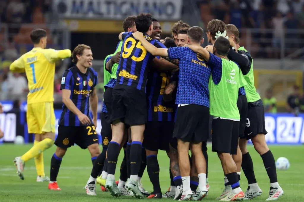 Giocatori dell'Inter si abbracciano e festeggiano insieme in campo durante una partita, con il portiere in giallo sullo sfondo