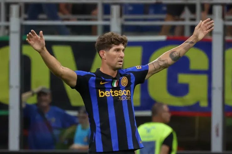 Giocatore dell'Inter con maglia a strisce blu e nera celebra durante una partita, braccia alzate.