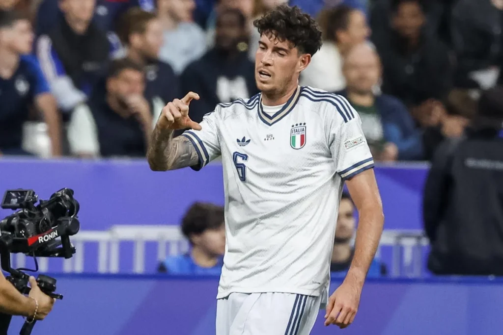Alessandro Bastoni con la maglia della Nazionale italiana numero 6 durante una partita, in campo con il pubblico sullo sfondo