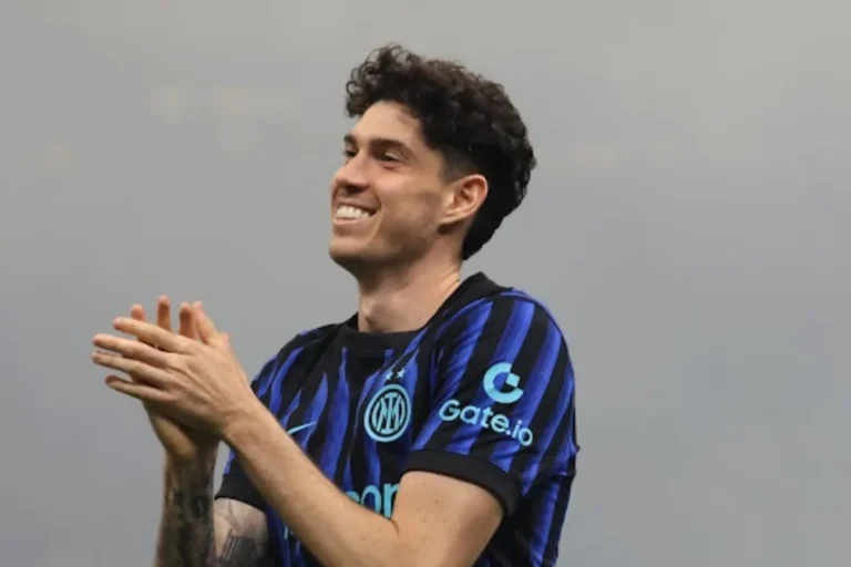 Alessandro Bastoni in maglia Inter a righe blu e nere applaude, sorridendo durante una partita