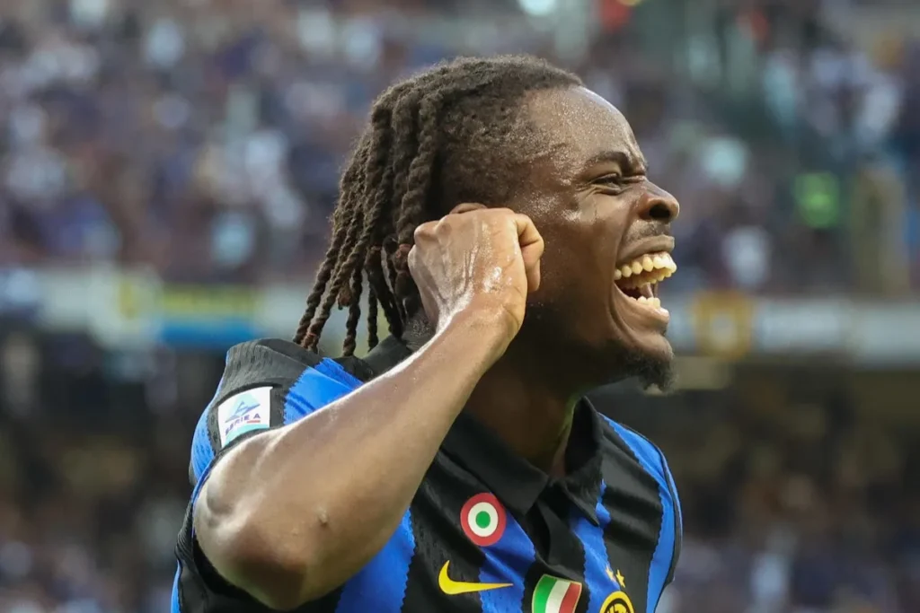 Bisseck esulta durante una partita dell'Inter, indossando la maglia nerazzurra con lo stemma della squadra