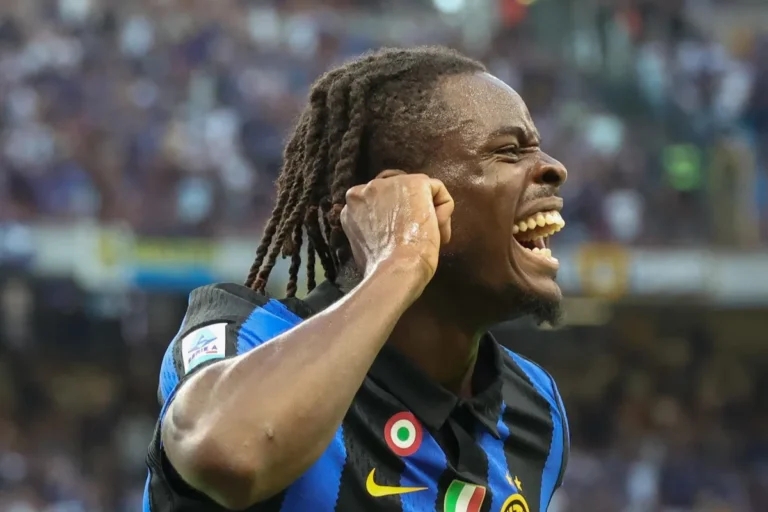 Bisseck esulta durante una partita dell'Inter, indossando la maglia nerazzurra con lo stemma della squadra