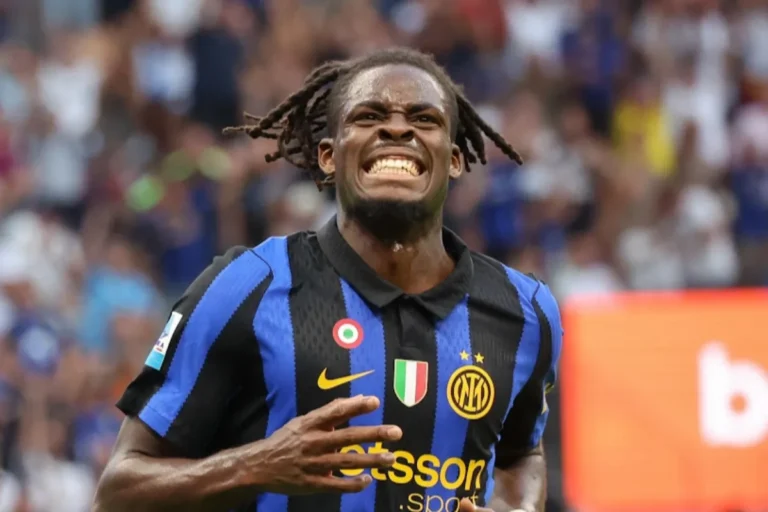 Calciatore dell'Inter con treccine e maglia nerazzurra, con espressione delusa e la mano alzata durante una partita