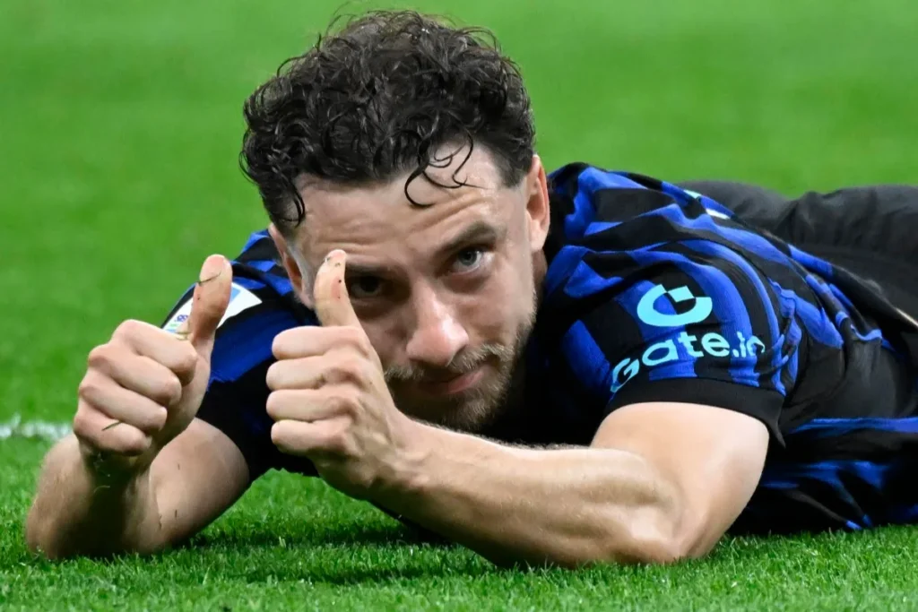 Carlos Augusto steso sull'erba del campo con maglia nero-azzurra, alza il pollice verso la fotocamera