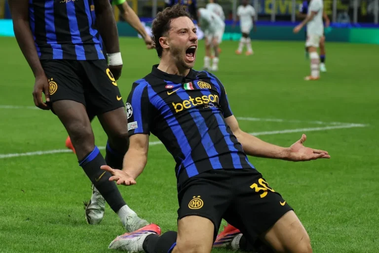 Calciatore dell'Inter con maglia a strisce nero-blu esulta sdraiato sul prato durante una partita