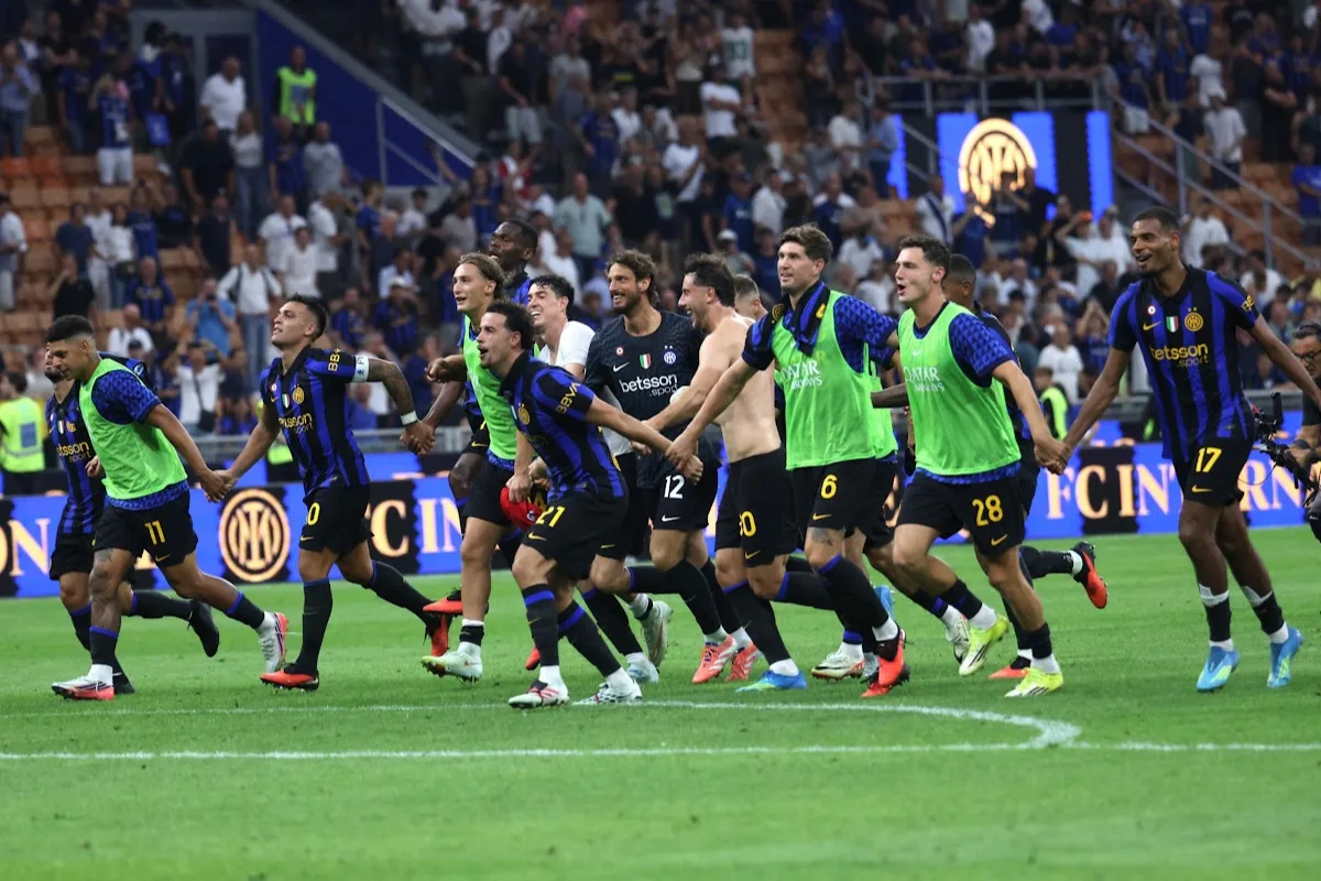 Giocatori dell'Inter esultano in gruppo sul campo davanti ai tifosi allo stadio, con maglie nerazzurre e pettorine verdi