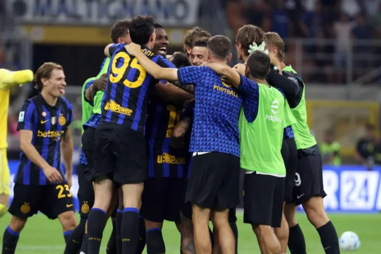 Giocatori dell'Inter abbracciati in un'esultanza di gruppo in campo, con maglie a righe nerazzurre e sponsor Betsson e Upower