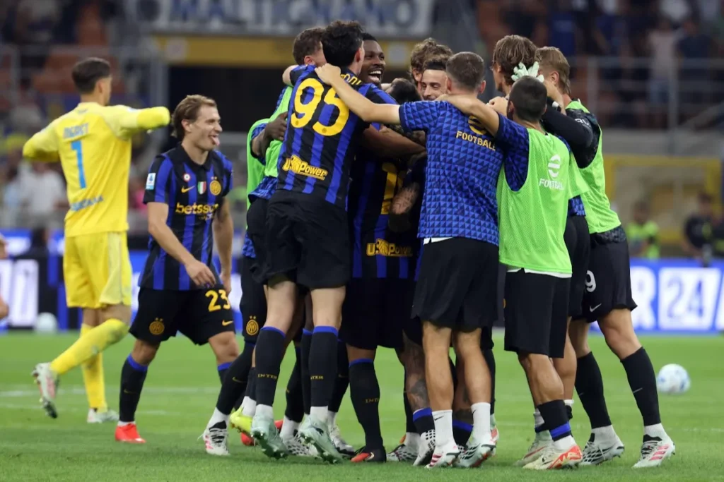 Giocatori dell'Inter abbracciati in campo a festeggiare, con la maglia numero 95 e un portiere in giallo sullo sfondo
