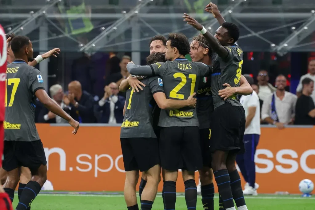 Giocatori dell'Inter abbracciati in campo durante l'esultanza di gruppo, con maglie grigie e numero 21 Jones in primo piano