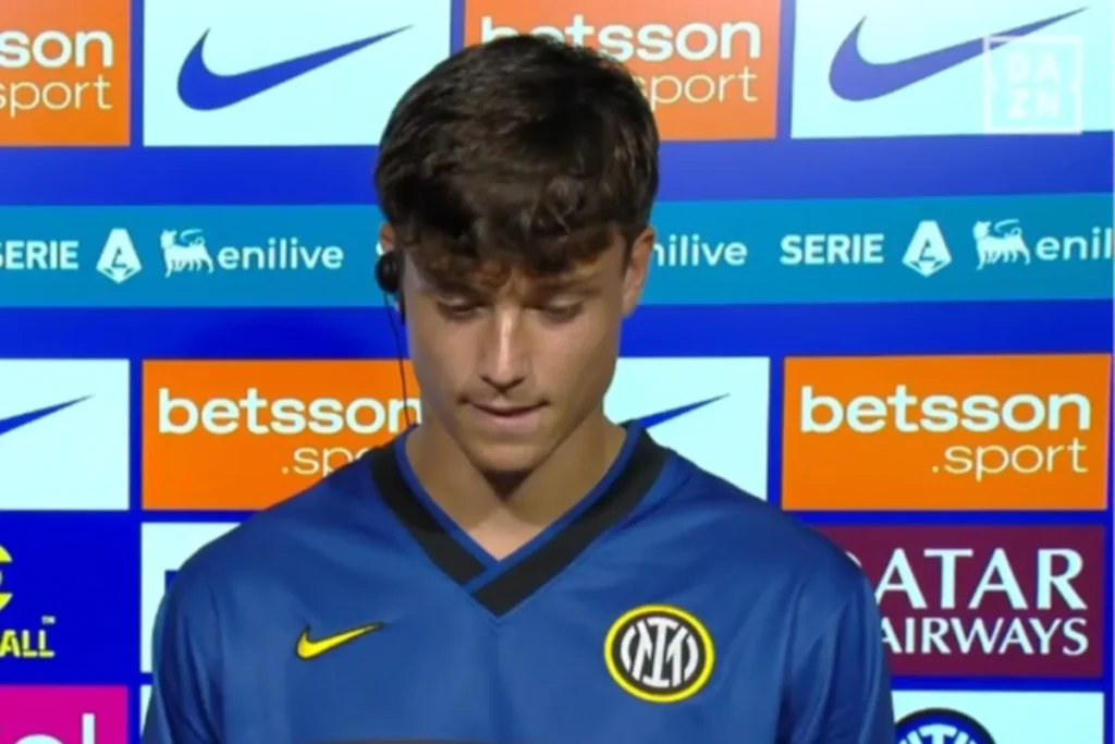 Giovane calciatore dell'Inter con maglia blu e auricolare durante un'intervista davanti ai pannelli sponsor Serie A