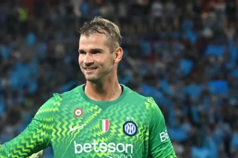Portiere dell'Inter con la maglia verde da portiere sorridente durante una partita, con tifosi sullo sfondo
