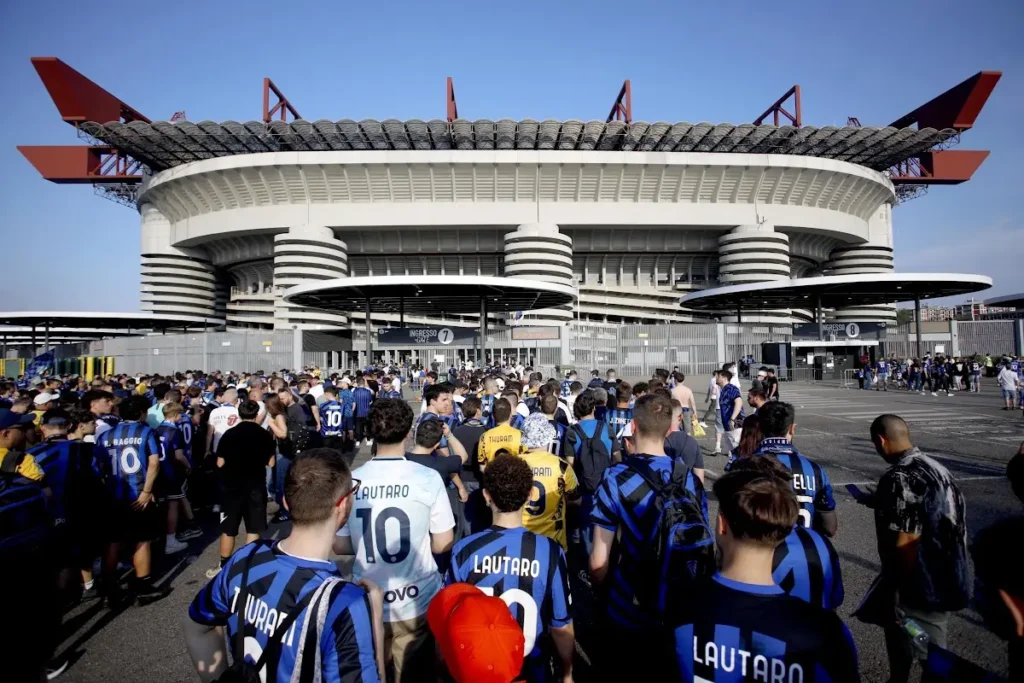 Tifosi interisti in fila davanti allo stadio San Siro con maglie nerazzurre, tra cui quelle con il nome Lautaro