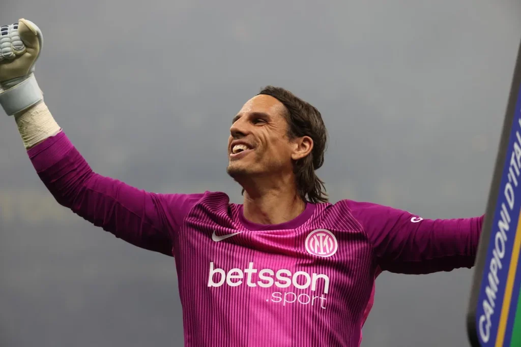 Portiere nerazzurro in divisa magenta con sponsor Betsson Sport esulta alzando il pugno accanto al banner Campioni d'Italia