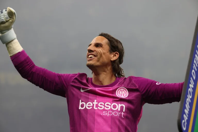 Portiere nerazzurro in divisa magenta con sponsor Betsson Sport esulta alzando il pugno accanto al banner Campioni d'Italia