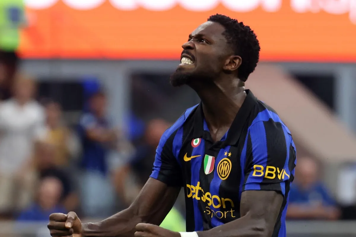 Giocatore dell'Inter con la maglia a strisce nerazzurre esulta a pugni stretti durante una partita