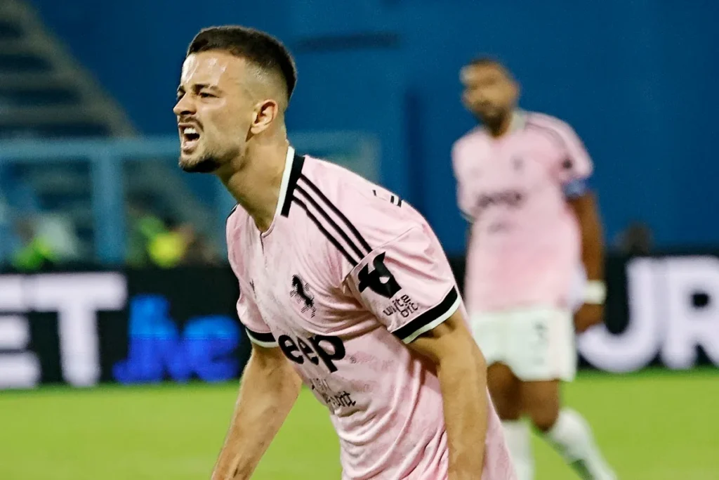 Zhegrova esulta in campo con la maglia rosa della Juventus durante una partita di calcio